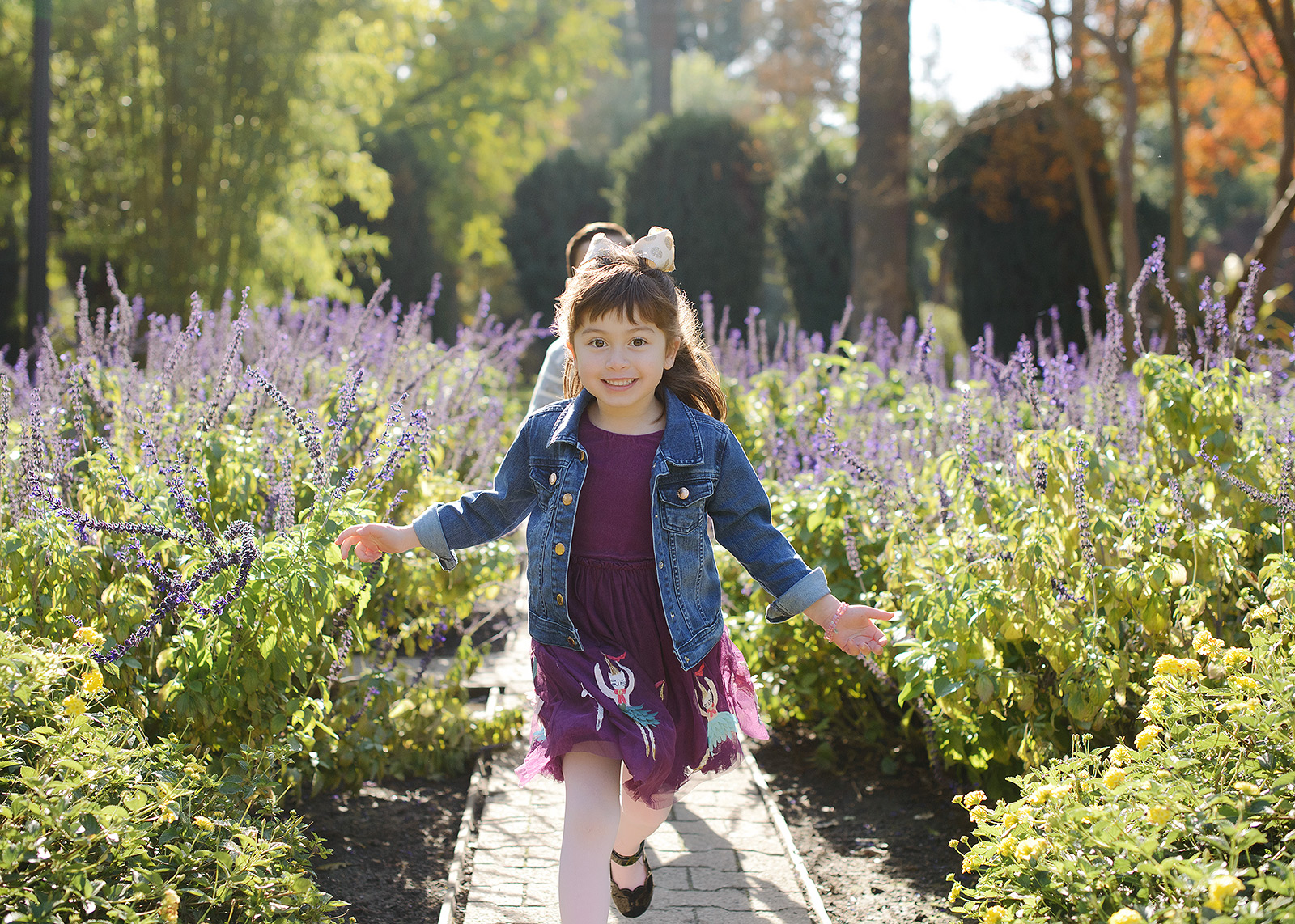 Daughter running through purple flower field wearing purple dress at State Capitol