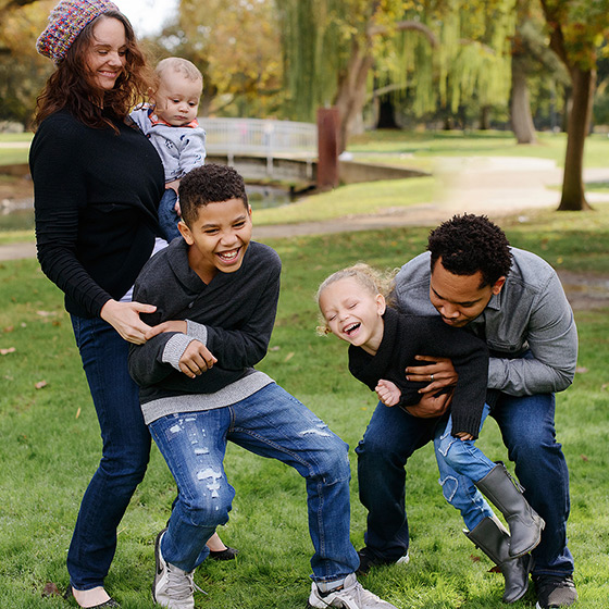 Happy mixed race family laughing in the park during Sacramento Fall season