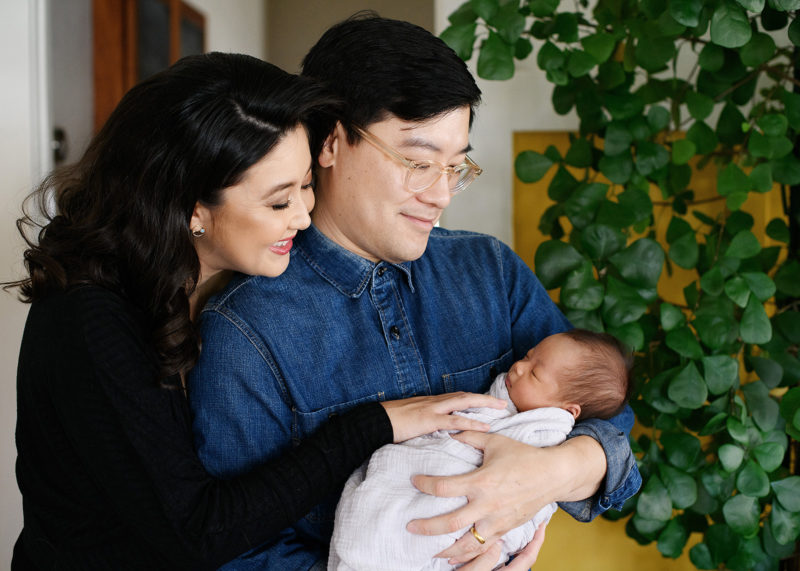Asian parents lovingly look at new baby daughter in home lifestyle session in Oak Park