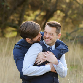Gay couple laughing and embracing during engagement shoot in Fair Oaks