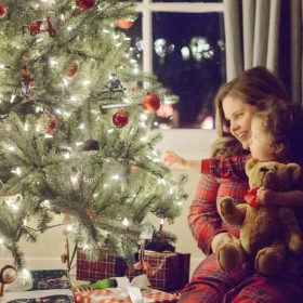 Mother and daughter in matching pajamas putting on Christmas tree ornaments