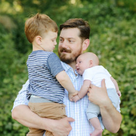 Dad holding his two boys in his arms as they hold hands lifestyle photo