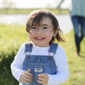Toddler girl wearing coveralls smiling in field of wildflowers in West Sacramento