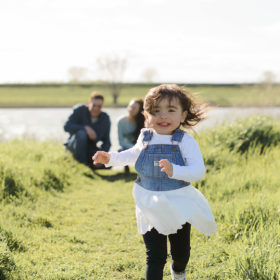 Toddler girl running in grassy field in West Sacramento