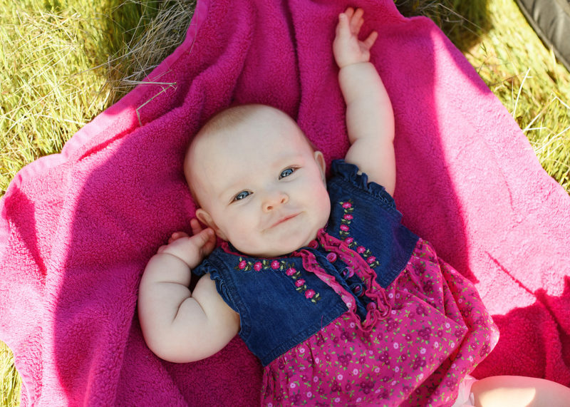 6 month baby girl lying on pink blanket on grass in Fair Oaks