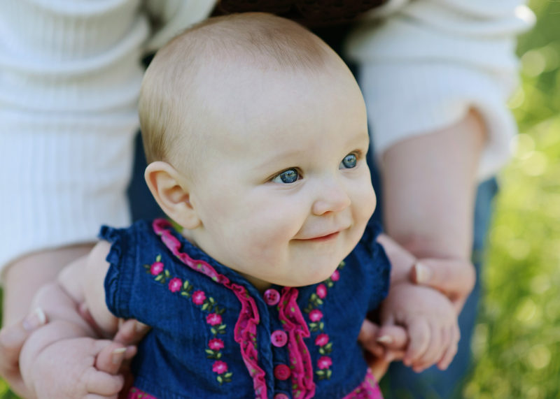 6 month baby girl close up as mom holds her on grass in Fair Oaks