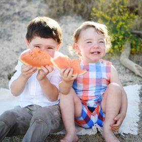 Brothers eating watermelon and smiling on the sandy beach in Folsom Lake State Recreation Area