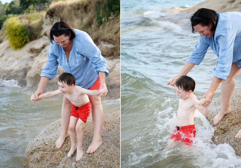 Mom guiding son through the water on beach in Folsom Lake State Recreation Area