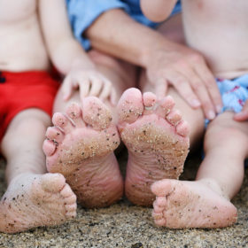Mom and sons sandy feet on the beach