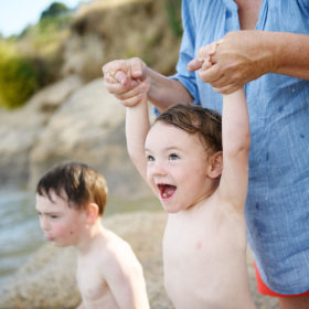 Boy smiling while mom is holding him at the beach in Folsom Lake State Recreation Area