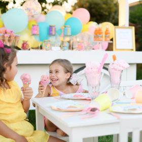 Little girl with ice cream on her nose laughing at party table