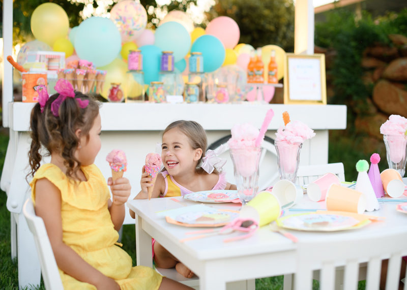 Little girl with icecream on her nose laughing at party table
