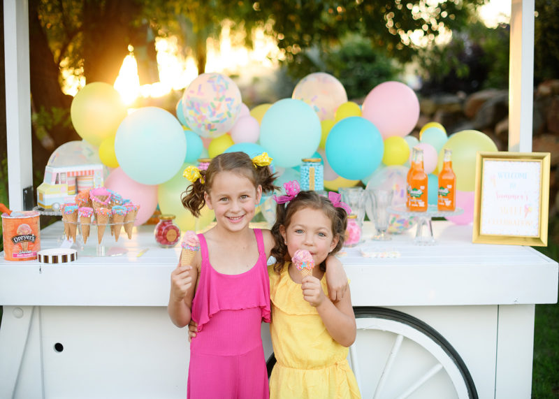 Little girls eating icecream in front of dessert display birthday party