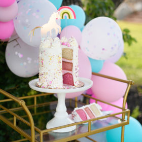Three layer pink cake with unicorn and rainbow topper detail
