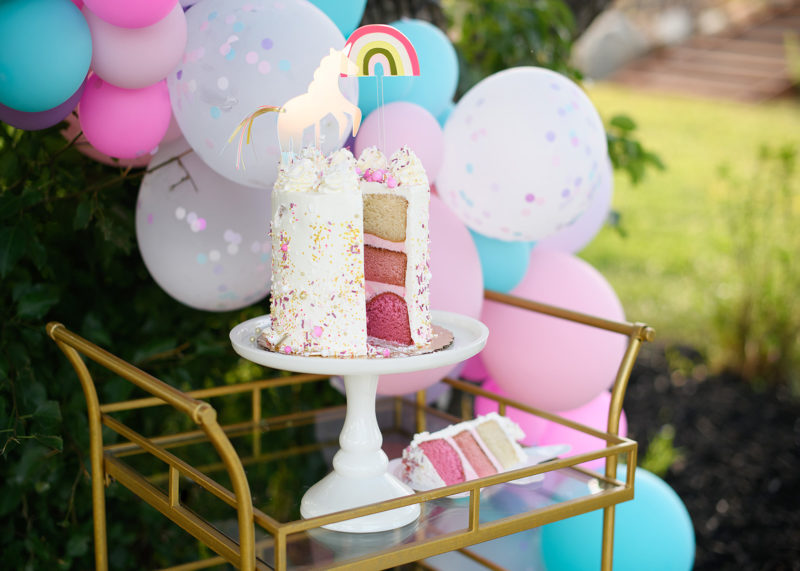 Three layer pink cake with unicorn and rainbow topper detail