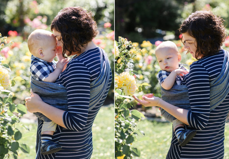 Mom wearing baby boy in wrap carrier while admiring yellow rose in McKinley Park