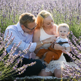 Mom and dad holding one year old smiling son in the Dixon lavender fields