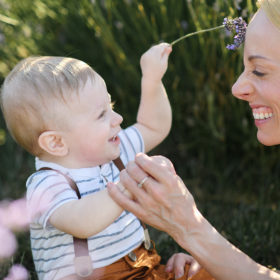 One year old boy holding sprig of lavender and making mom laugh in Dixon
