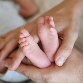 Close up of newborn baby feet being held by mom’s hands
