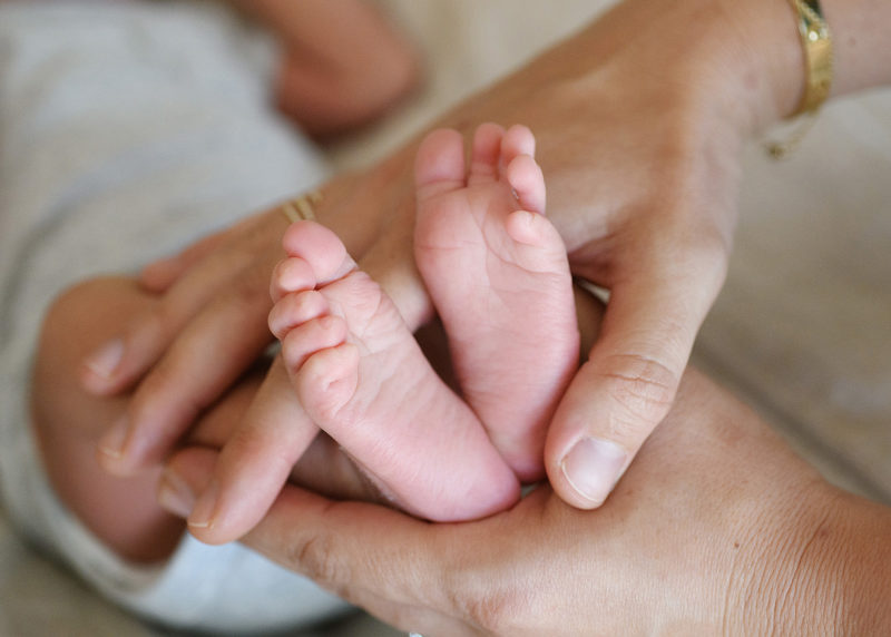 Close up of newborn baby feet being held by mom's hands