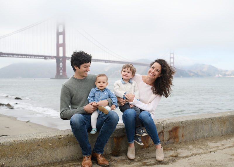 Family posing in front of foggy Golden Gate Bridge in San Francisco