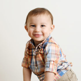 Baby boy sticking tongue out and smiling in studio portrait