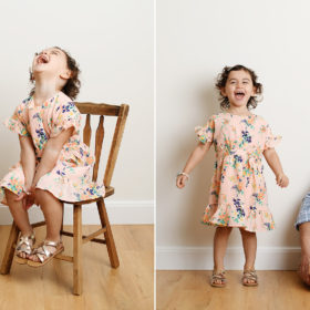 Big sister wearing floral dress laughing and sitting on chair in studio