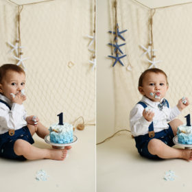 Baby boy eating frosting off cake for nautical themed cake smash in studio
