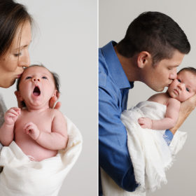 Mom and dad holding and kissing yawning newborn baby girl