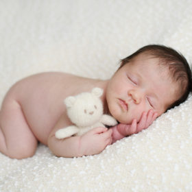 Sleeping newborn baby with teddy bear on white blanket in Sacramento studio