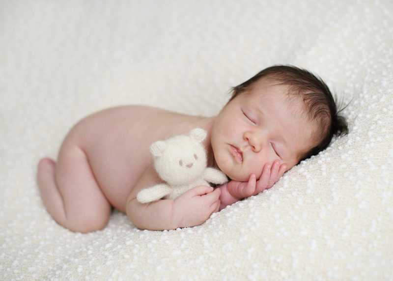 Sleeping newborn baby with teddy bear on white blanket in Sacramento studio