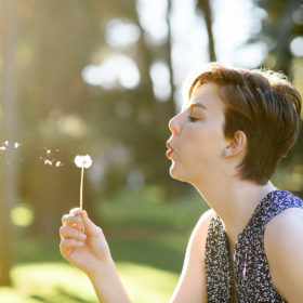 Teen girl blowing on dandelion outside of State Capitol