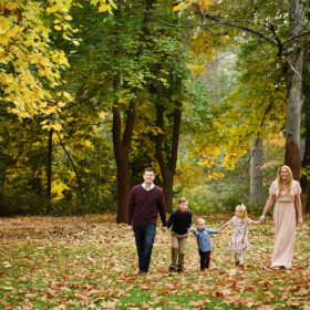 Family walking on fallen autumn leaves in the grass among foliage in Grass Valley