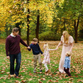 Family laughing and enjoying each other on the grass where there are autumn leaves in Grass Valley