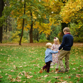Siblings hug each other on the grass with fall foliage and autumn leaves on ground in Grass Valley