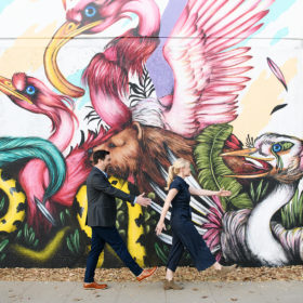 Engaged couple walking along Mateus Bailon mural on R Street in Sacramento