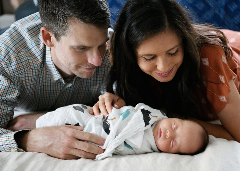 Mom and dad lovingly look at newborn baby boy on bed in Sacramento home