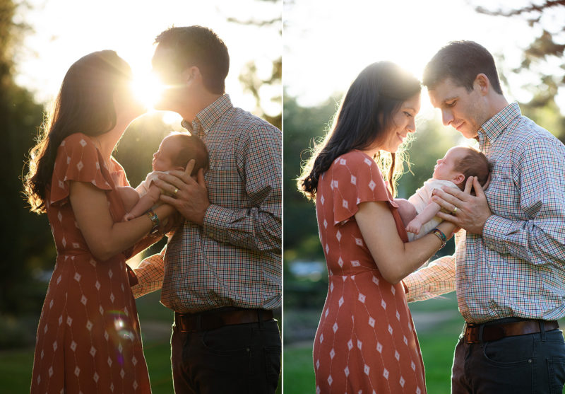 Mom and dad kiss and hold newborn baby in front of warm sunset light in Sacramento