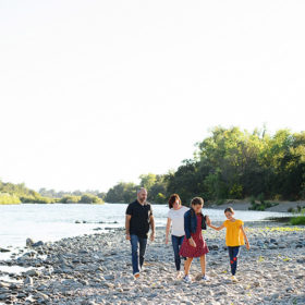 Family walking along river on smooth rocks