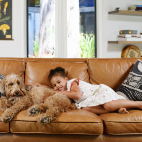 Daughter and dog lying down on brown leather couch in Mendocino home