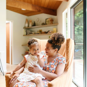 Mom and daughter sitting on armchair surrounded by natural light in Mendocino home