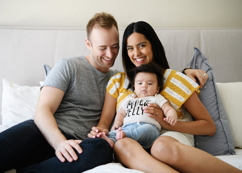 Mom and dad snuggle with baby boy in bed in Sacramento home