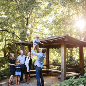 Dad lifting up son in air while grandparents, mom and sister watch next to pergola in Quarryhill Botanical Garden Sonoma
