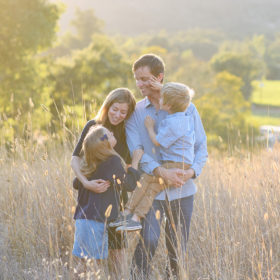 Family hugging in tall yellow grass during sunset in Quarryhill Botanical Garden Sonoma
