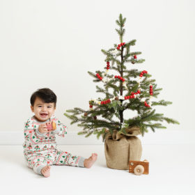 Baby boy wearing pajamas next to Christmas tree and toy camera in Sacramento studio
