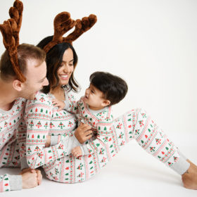 Family wearing Christmas pajamas and reindeer antlers while holding baby boy