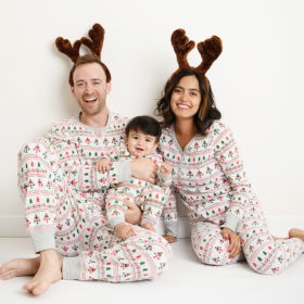 Family wearing matching Christmas pajamas with baby boy smiling at camera in Sacramento studio