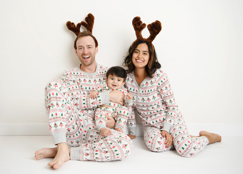 Family wearing matching Christmas pajamas with baby boy smiling at camera in Sacramento studio