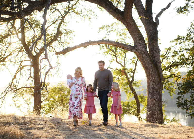 Family walking hand in hand under a large tree in Folsom
