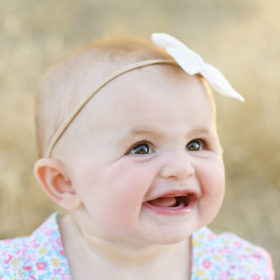 Close up of baby girl smiling wearing a bow in Folsom